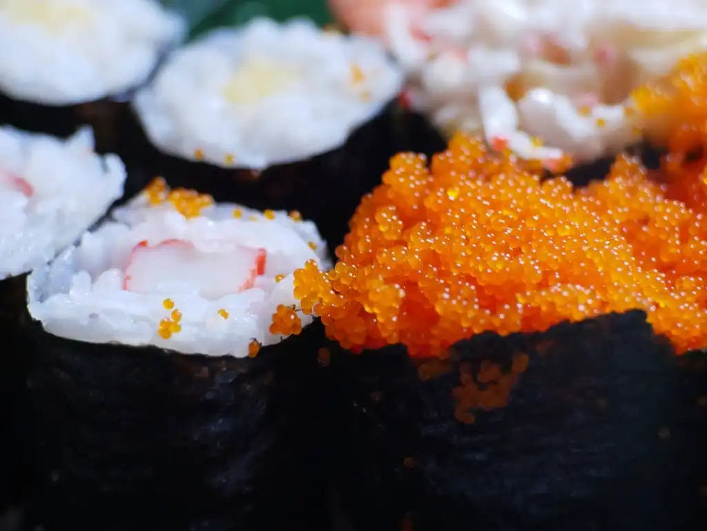 Close-up of sushi rolls topped with orange fish eggs